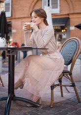 A lady wearing a tulle skirt drinks coffee.